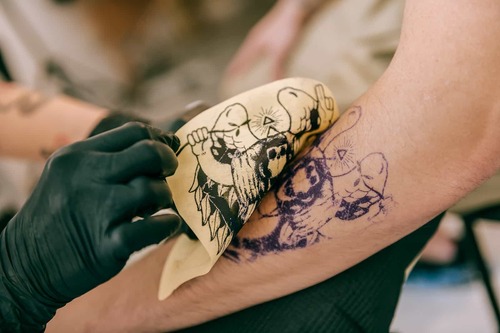 applying tattoo on hand via stencil